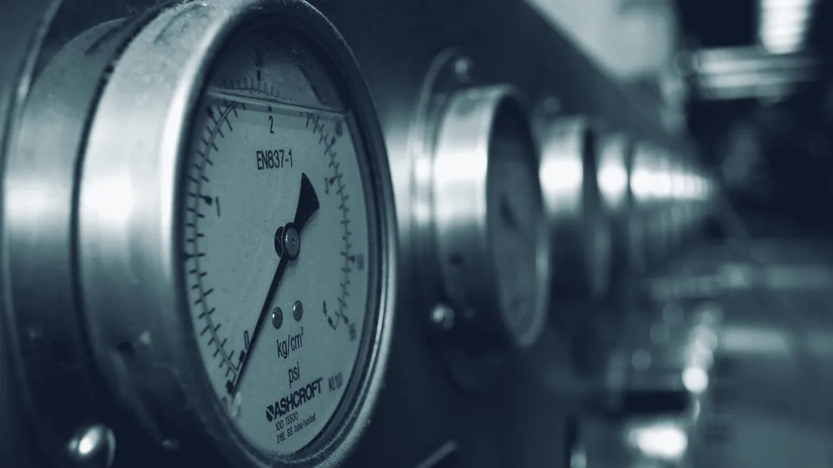 Einzelnes rundes Manometer an einer Rohrleitung, schwarzweiß