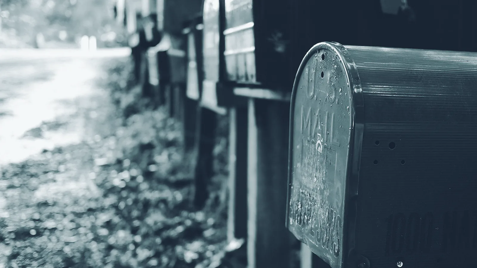 Eine Reihe verwitterter Briefkästen am Straßenrand, der vorderste im Anschnitt