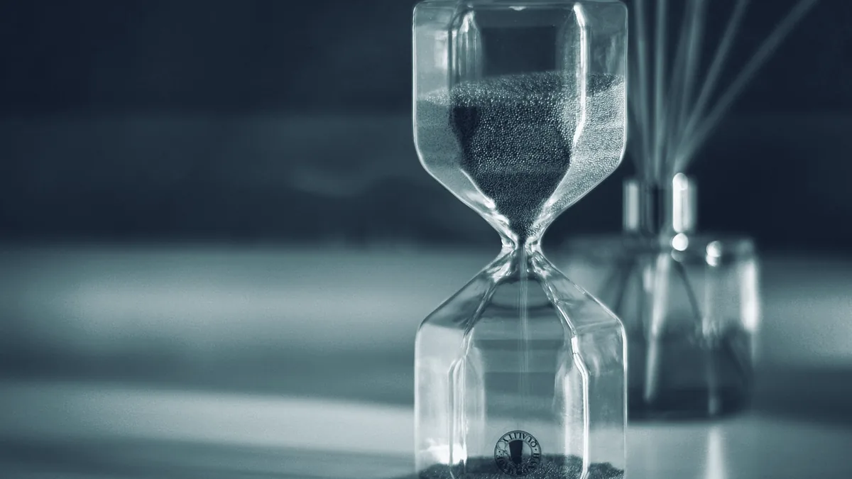 Eine Sanduhr, deren Sand gerade durch die Engstelle in die untere Kammer rieselt