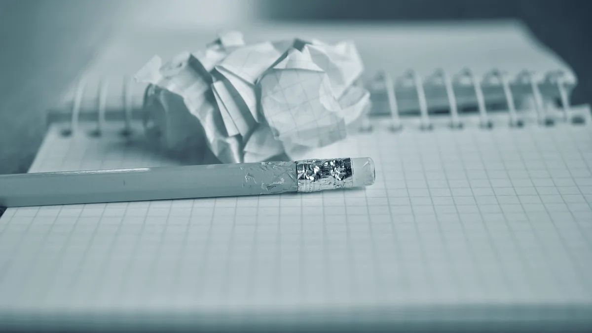 Ein kariertes Notizbuch mit Bleistift und einem zerknüllten Blatt Papier darauf