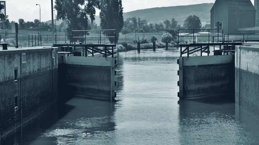 Geschlossenes Schleusentor in einem Kanal, davor ruhiges Wasser