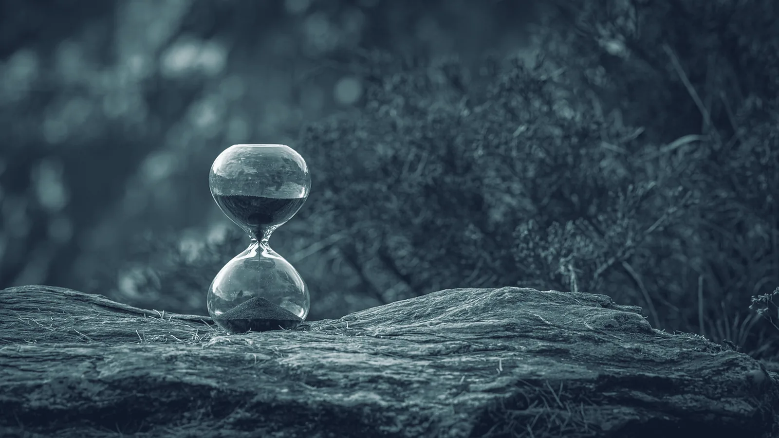 Sanduhr auf einem Felsen, im oberen Glas liegt noch Sand