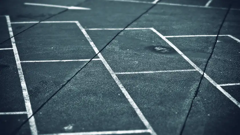 Leere, weiß markierte Stellflächen auf nassem Asphalt